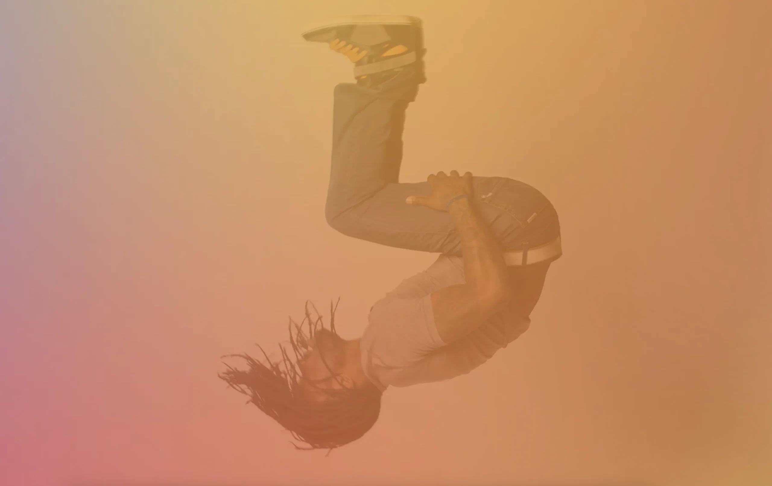 Dancer flipping against a warm purple and gold gradient